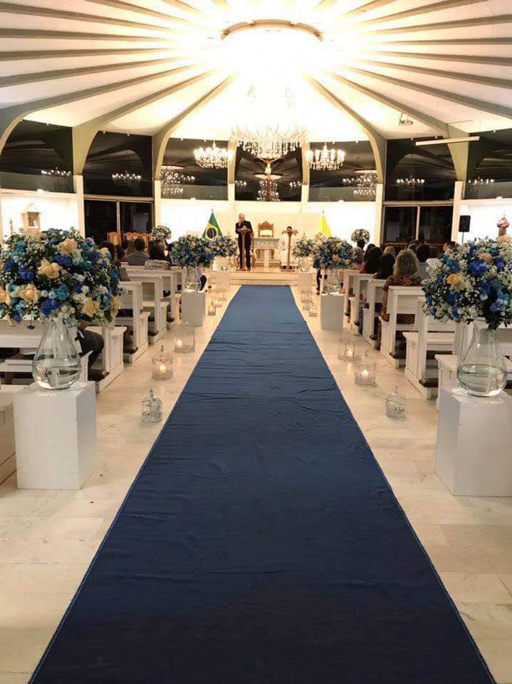 Cerimônia decorada com tapete azul e arranjos de flores